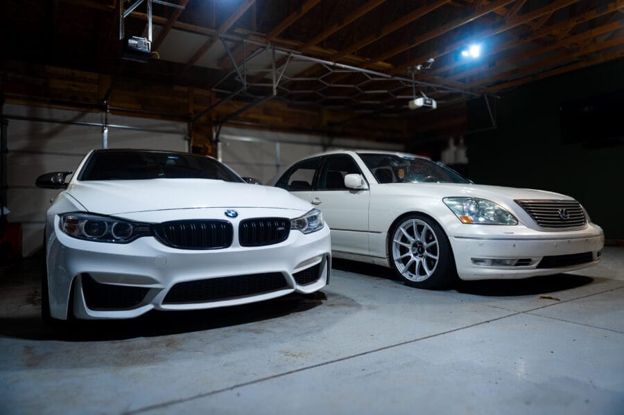 White BMW F82 M4 and white Lexus LS430 parked side by side in a garage