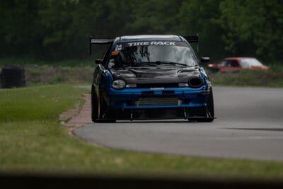 Head-on track photo of a 1999 Dodge Neon showing four front splitter support rods