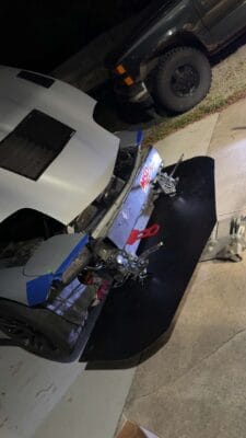 Homemade carbon splitter test-fitted beneath the exposed front structure of a 2000 Chevrolet Corvette C5