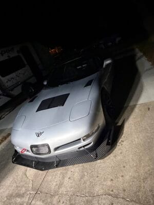 Front three-quarter view of a silver 2000 Chevrolet Corvette C5 with its carbon splitter and support rods installed