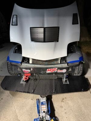 Bumper-off overhead view of a C5 Corvette showing the fabricated splitter brackets and detached carbon splitter