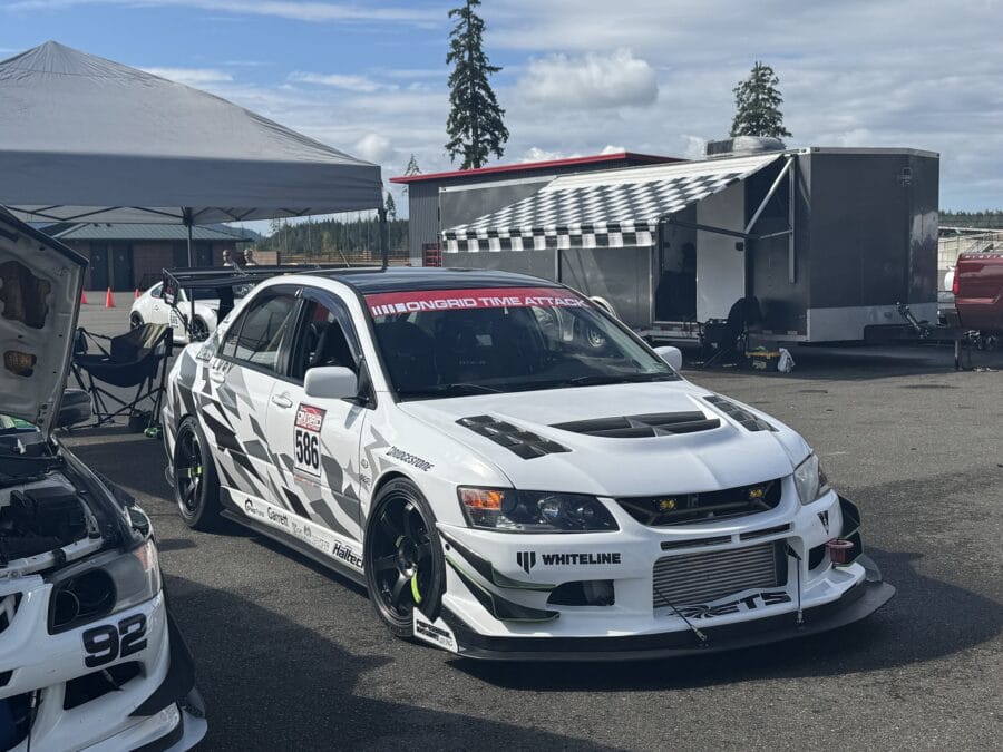 Front three-quarter view of a white 2005 Mitsubishi Lancer Evolution VIII with a custom front splitter at the track
