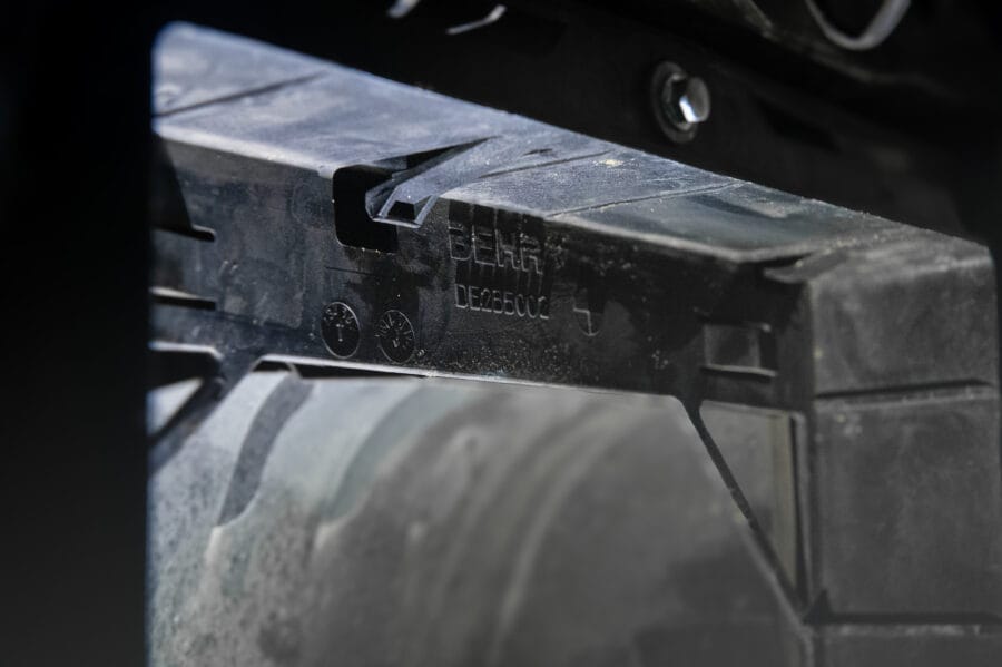 Close-up of a black BEHR radiator's molded plastic retaining clips, or "fangs," used to hold the auxiliary cooler in place on a BMW F82 M4.