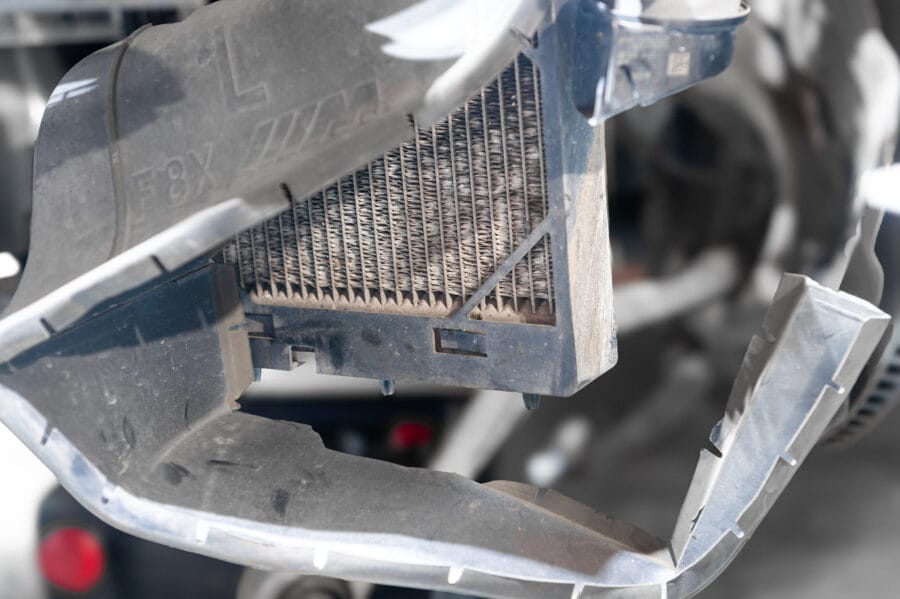 Close-up front view of a BMW F82 M4's auxiliary cooler core mounted in its factory ducting, with the F8X part marking visible on the plastic frame.