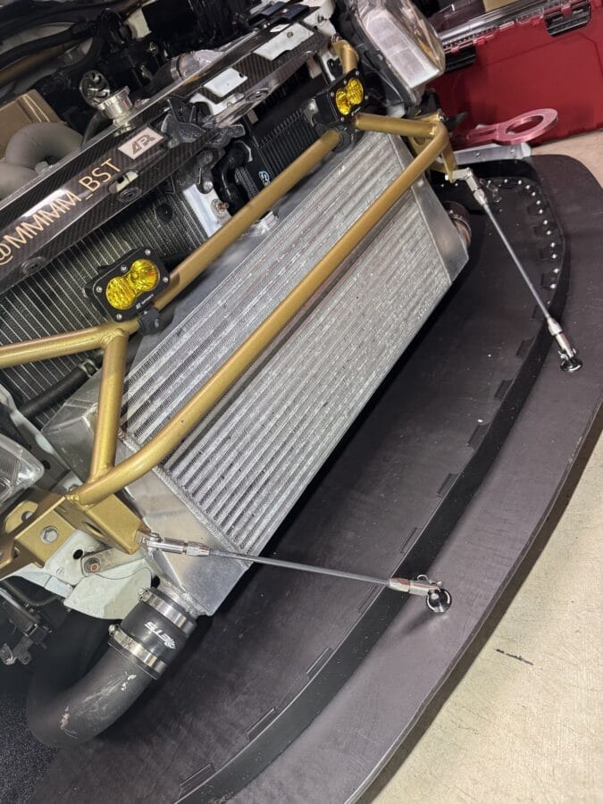 Bumper-off overhead view of splitter support rods attached near the Cusco power brace on a Mitsubishi Evo 8