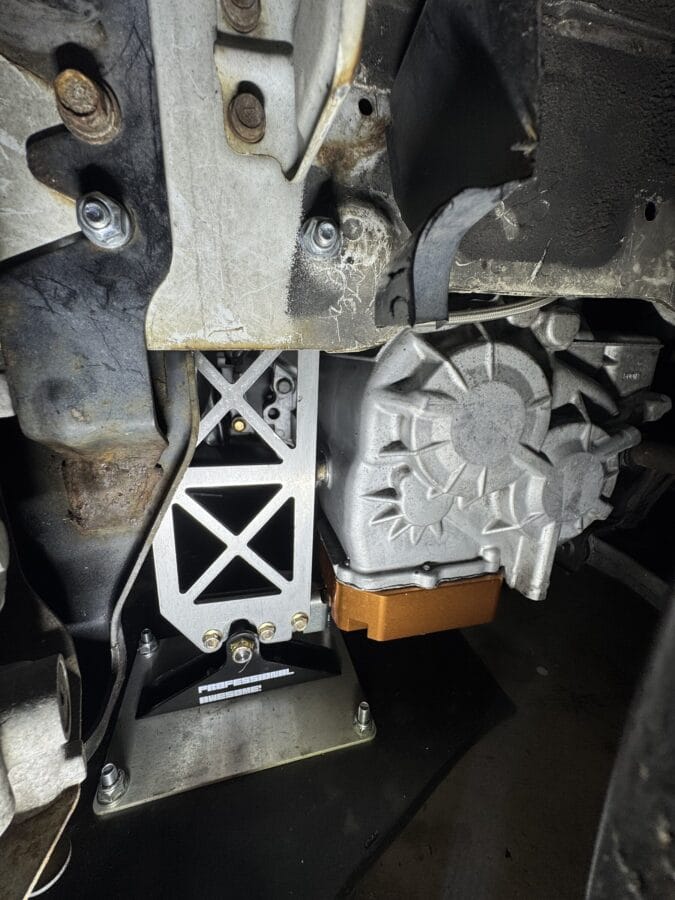 Underside detail of a quick-release splitter bracket bolted to the frame rail of a Mitsubishi Evo 8