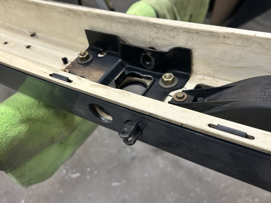 Close-up of a support rod clevis protruding from Drew’s BMW E30 front bumper assembly.