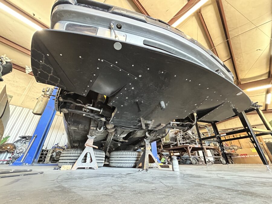 Wide underside view of Drew’s 1989 BMW E30 325is showing the installed ABS splitter, diffuser openings, and support rods.
