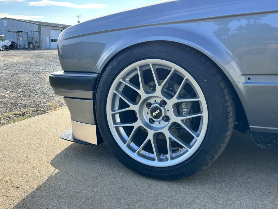 Side view of Drew’s BMW E30 front wheel showing the splitter edge and aluminum air dam profile.