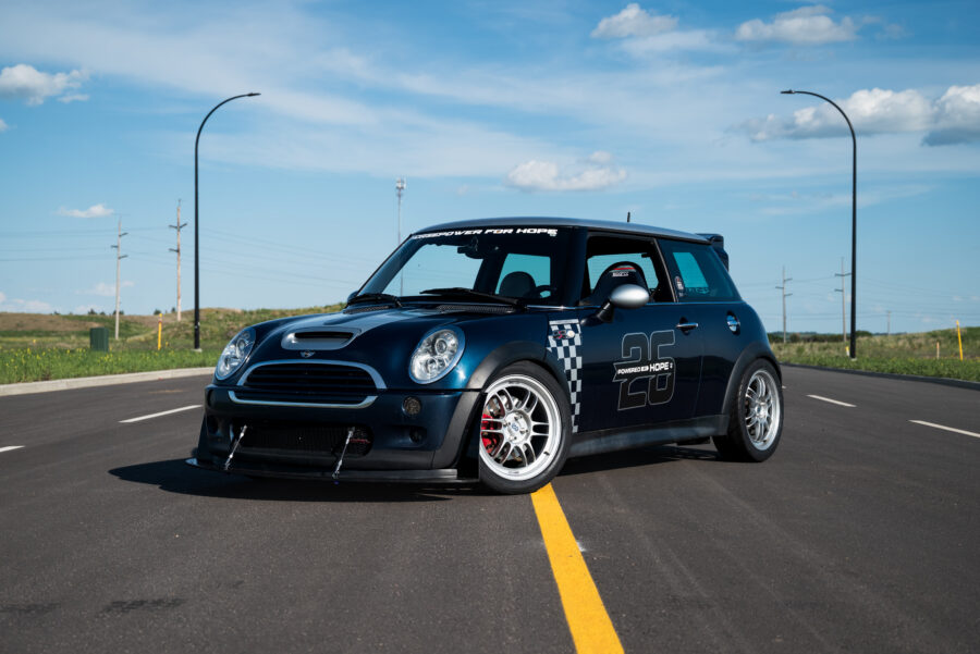 Dameon Priebe’s blue 2006 MINI Cooper S JCW R53 with front splitter and two support rods, viewed from the front three-quarter angle