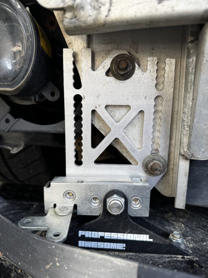 Close-up of the quick-release splitter mount on the left side of the photo beneath the MINI’s crash bar