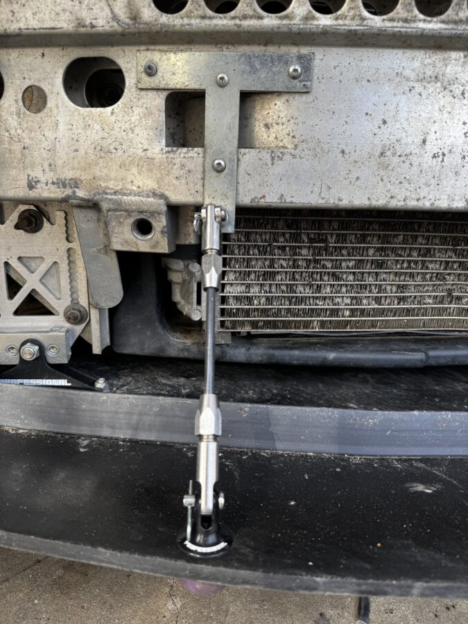 Splitter support rod connected to a hardware-store T-plate on the MINI’s crash bar, with the bumper removed