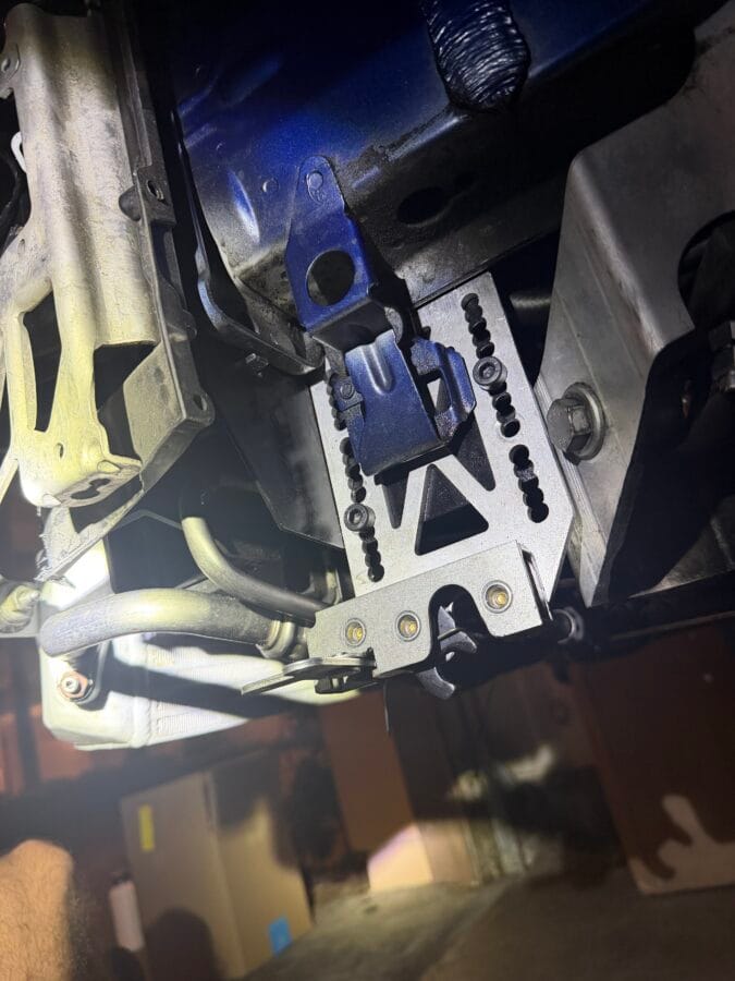 Close-up of a Professional Awesome quick-release splitter mount attached to a Condor frame-rail adapter on a BMW E82.